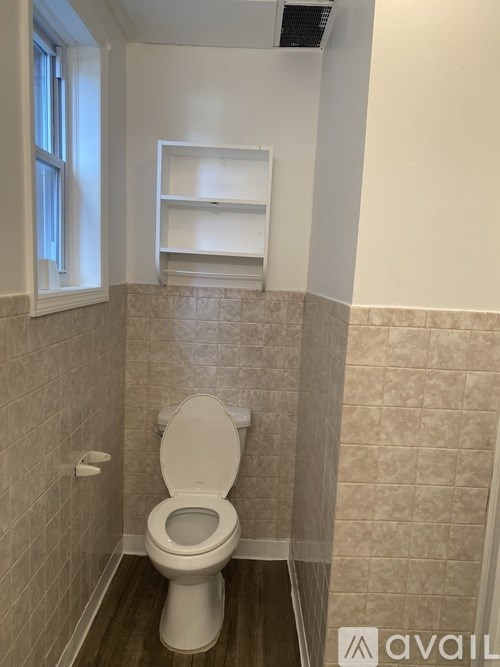 A bathroom with a toilet and a shelf above it.