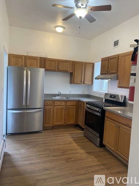 A kitchen with wooden cabinets and a stainless steel refrigerator.