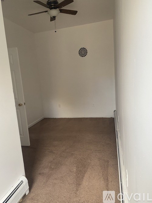 A room with a ceiling fan and a round vent on the wall.