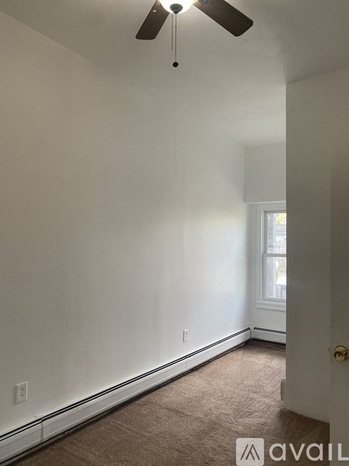 A room with a carpeted floor and a ceiling fan.