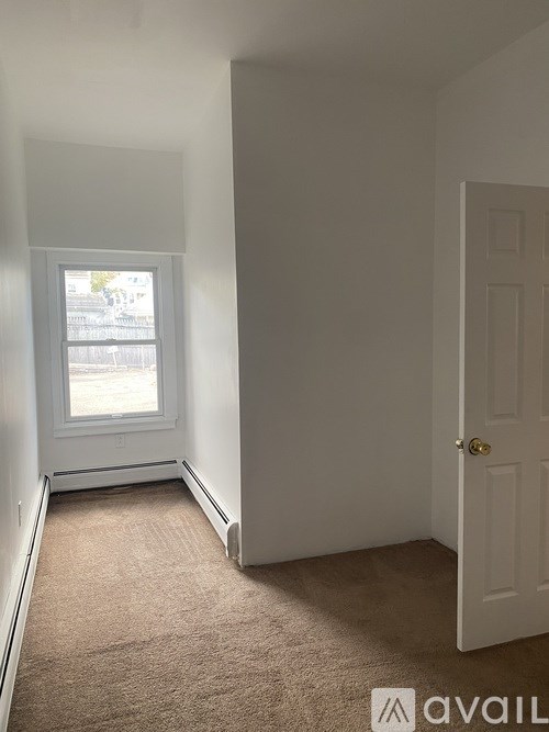 A room with a carpeted floor, a window, and a door.