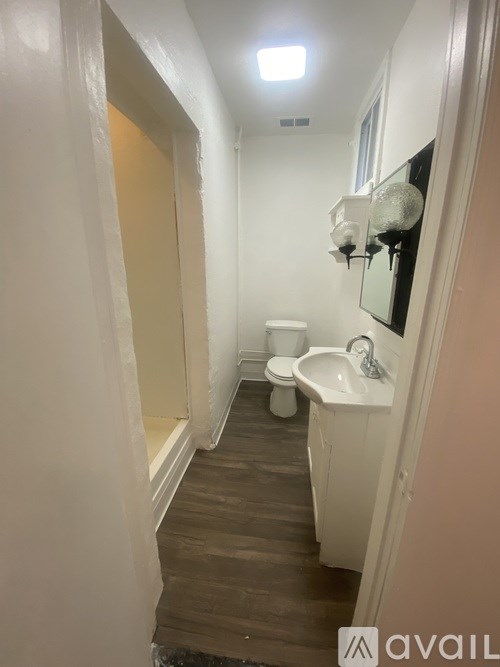 A bathroom with a toilet, sink, and mirror.