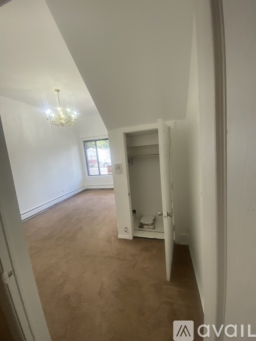 A room with a chandelier and a small bathroom with a toilet and a sink.