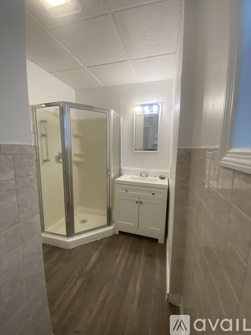 A bathroom with a walk-in shower and a vanity with a mirror.