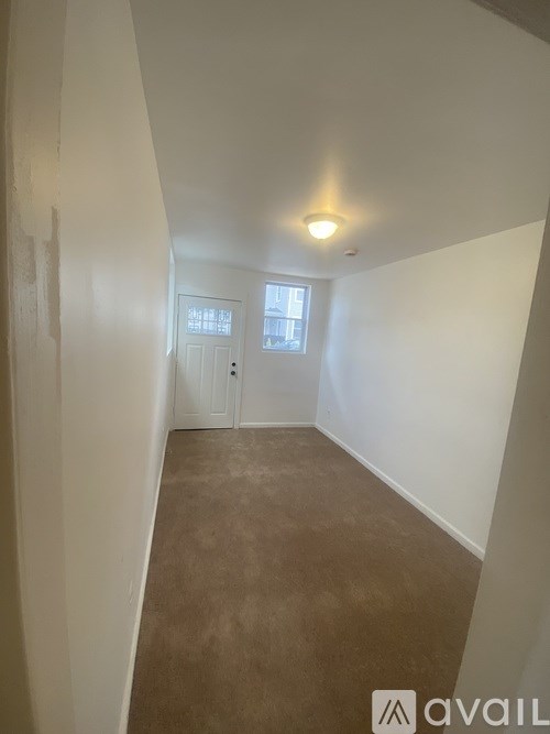 A hallway with a carpeted floor and a light on the ceiling.