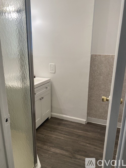 A bathroom with a white cabinet and a glass shower door.