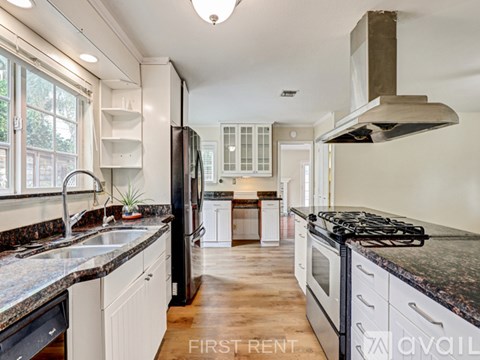 A kitchen with a black refrigerator and a black stove top oven.