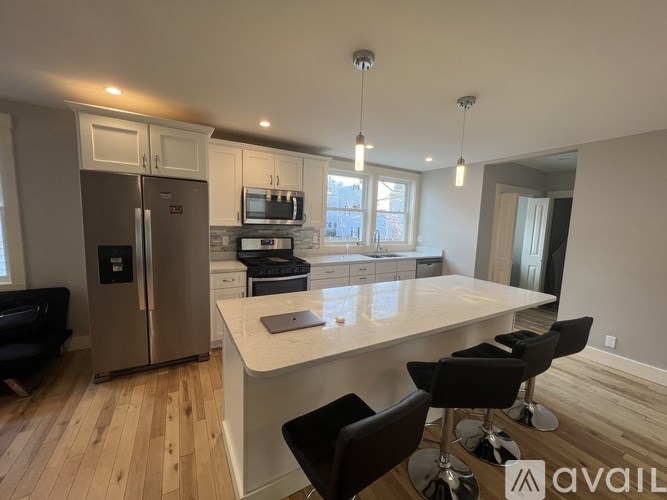 A kitchen with a refrigerator, microwave, and a table with chairs.