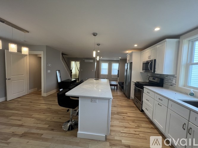 A kitchen with a white island and wooden flooring.