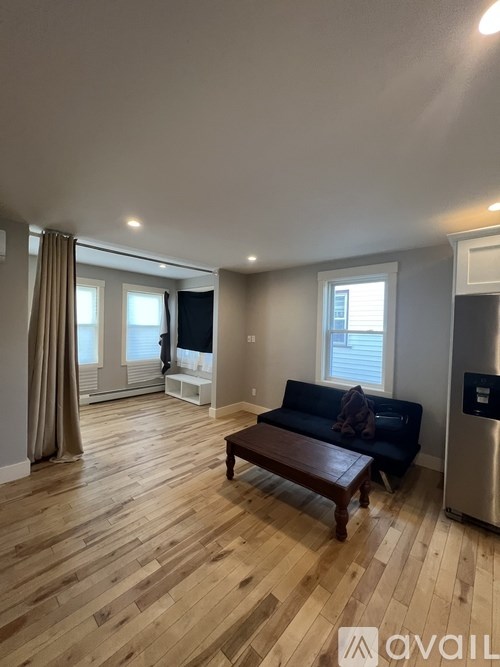 A living room with a couch, a table, and a window with curtains.