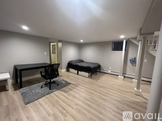 A room with a black table and a black chair with a grey rug in front of it.