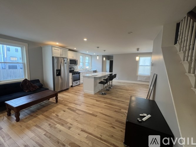 A spacious kitchen and living room with wooden flooring and modern appliances.