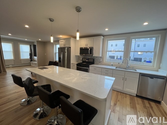 A modern kitchen with a large island and black chairs.