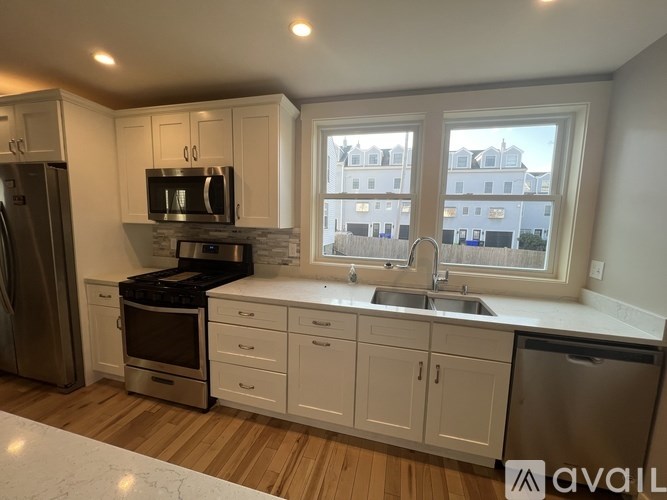 A kitchen with white cabinets and a stainless steel refrigerator.