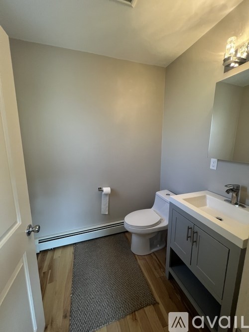 A bathroom with a toilet, sink, and mirror.