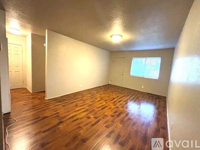 A room with wooden flooring and a window with blinds.
