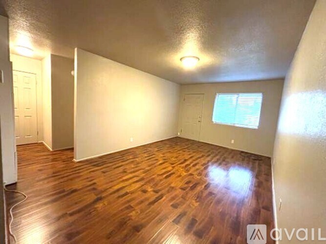 A room with wooden flooring and a window with blinds.
