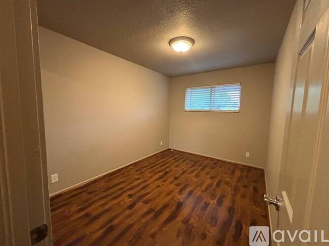 A room with wooden flooring and a window with blinds.