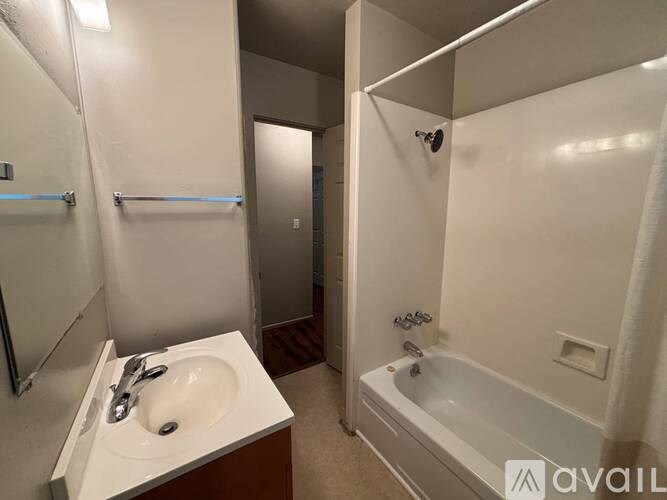 A bathroom with a sink, mirror, and bathtub.
