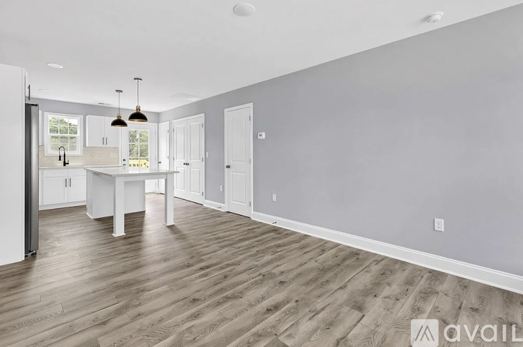 A spacious room with wooden flooring and white walls.