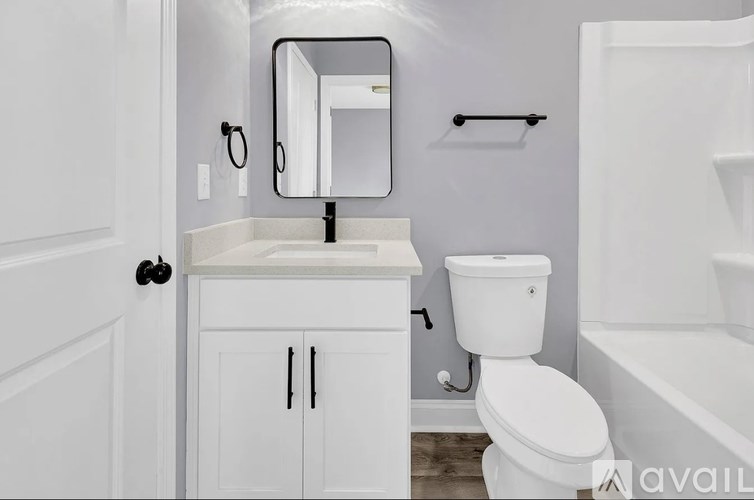 A white bathroom with a toilet, sink, and mirror.
