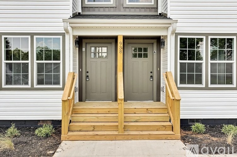 A house with a grey front door and a wooden staircase leading to it.