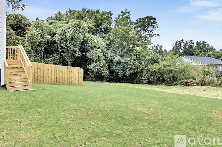 A backyard with a wooden deck and a large grassy area.