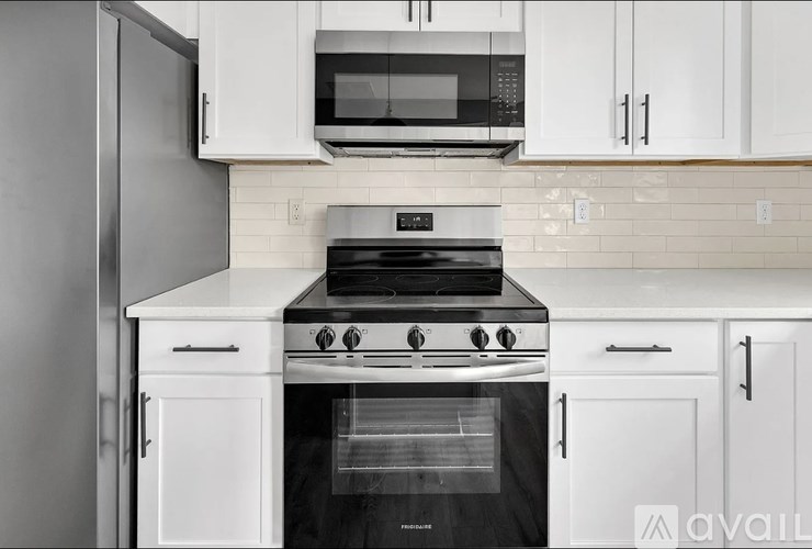 A modern kitchen with a stove, microwave, and cabinets.