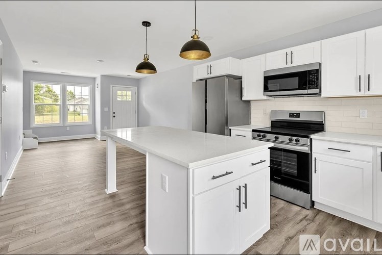 A modern kitchen with white cabinets and a wooden floor.