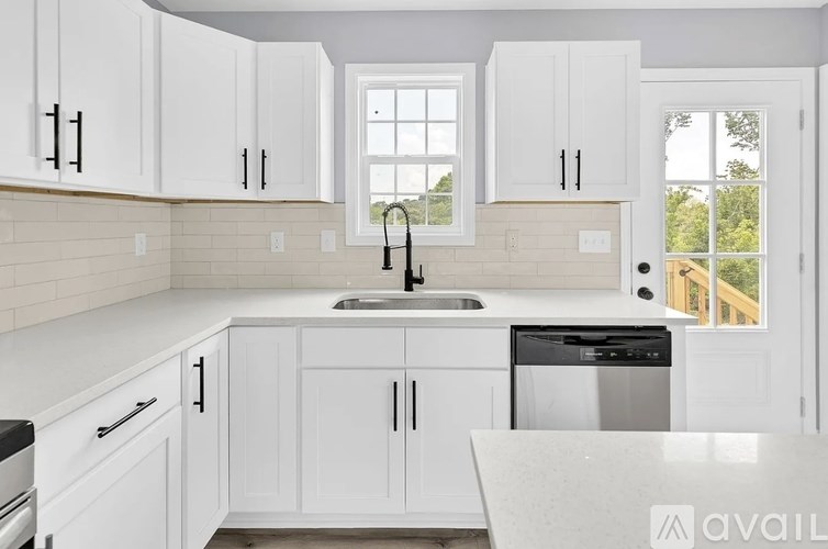 A kitchen with white cabinets and a marble countertop.