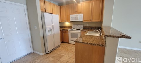 A kitchen with a granite counter top and a refrigerator.