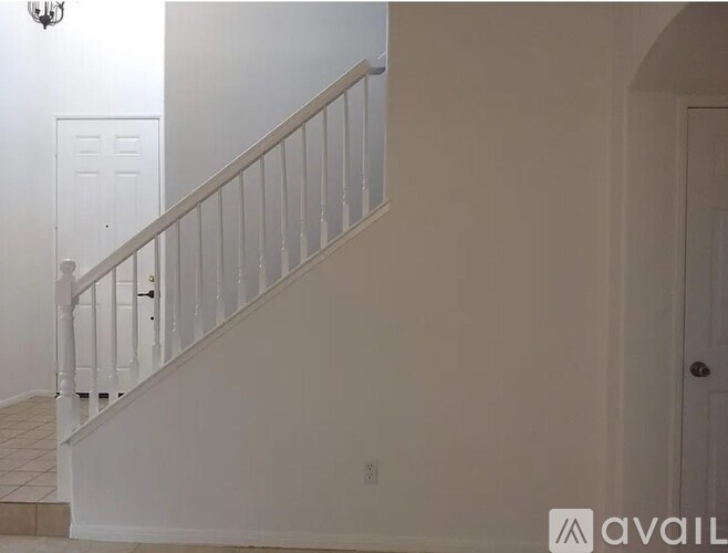 A staircase with white railings and a white door on the left side.