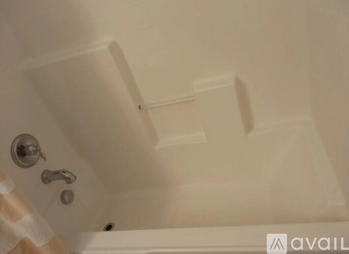 A white bathtub with a silver faucet and a shower head.