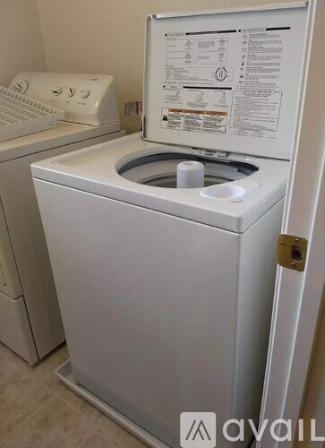 A white washing machine with a door open showing the instruction manual.