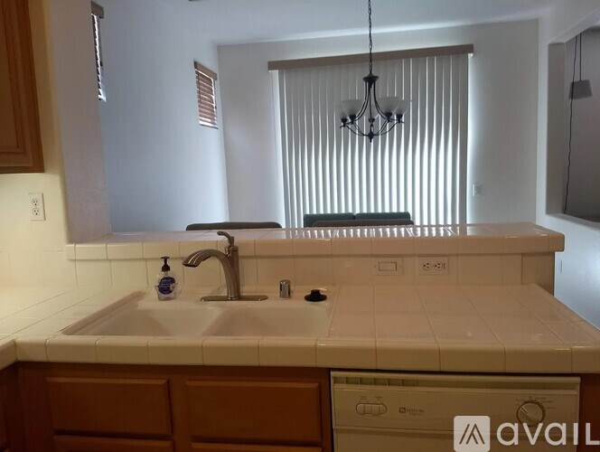 A kitchen with a sink and a window with blinds.