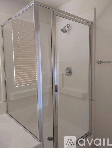 A shower stall with a glass door and a silver handle.