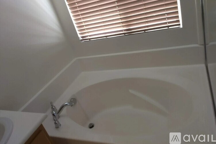 A white sink under a window with blinds.