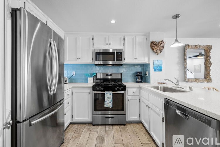 A kitchen with a stainless steel refrigerator and white cabinets.