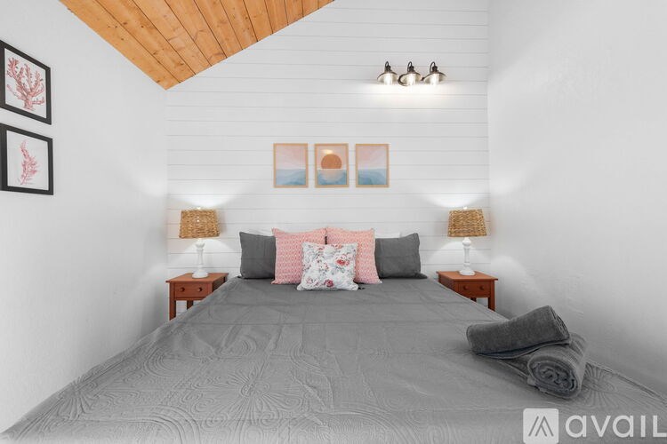 A bedroom with a large bed and two lamps on either side.