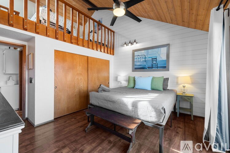 A bedroom with a bed, a ceiling fan, and a painting on the wall.
