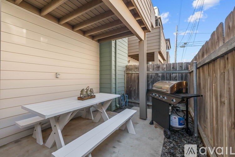 A patio with a table, bench, and grill.