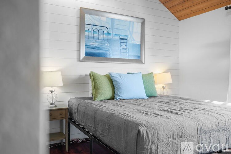 A bedroom with a bed, two lamps, and a framed picture on the wall.