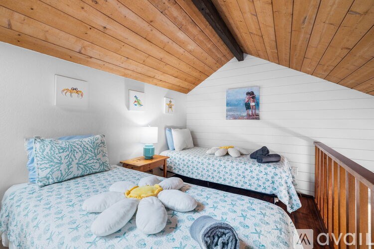 A bedroom with two beds and a wooden ceiling.