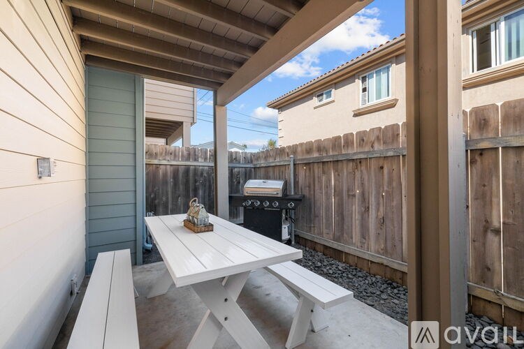 A white table with a small object on it is in the foreground of a patio area.