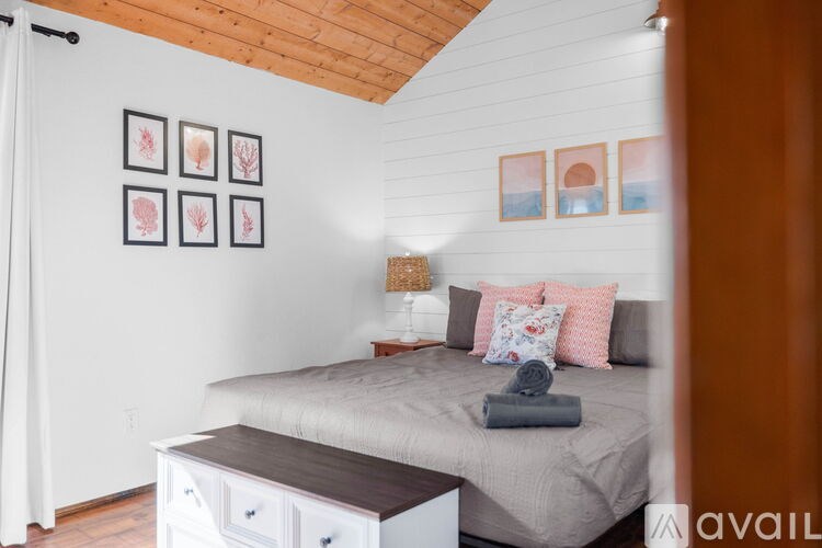 A bedroom with a bed, nightstand, and pictures on the wall.