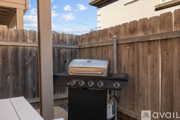 A black barbecue grill with a silver griddle on top is on a patio.