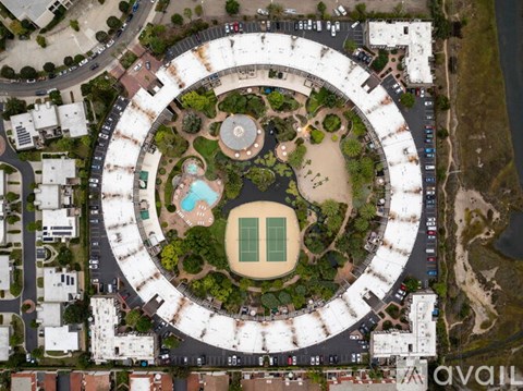 A bird's eye view of a roundabout with a tennis court in the center.