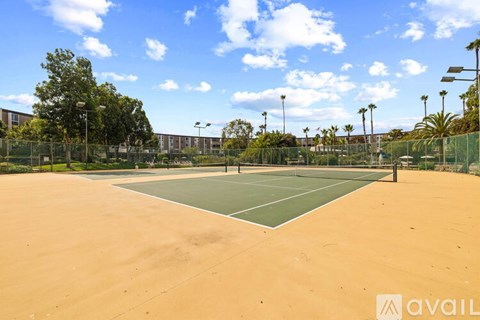 Tennis court with a net and trees in the background.