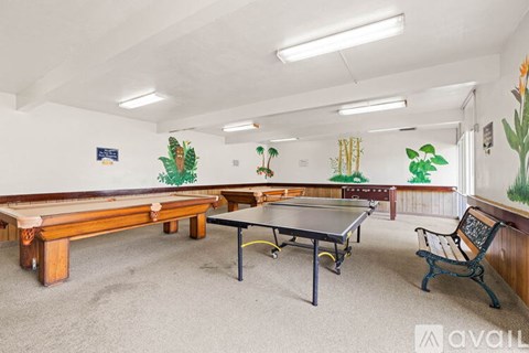 A room with a pool table, air hockey table, and a bench.