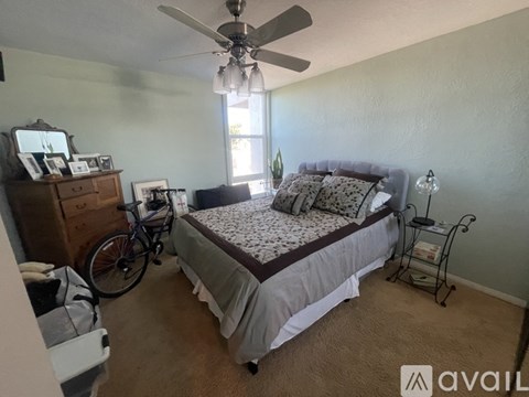 A bedroom with a bed, a fan, and a bicycle.